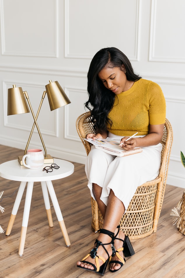 Maintain Your Health and Wellness: Black woman with long hair sitting writing in a journal planner 